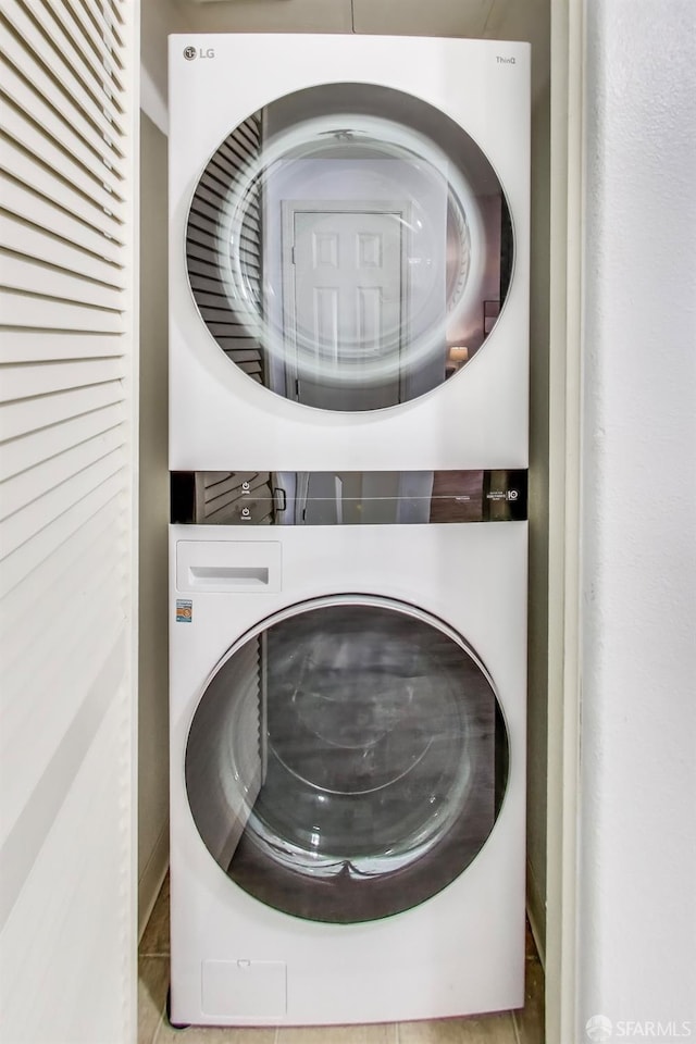 laundry area with stacked washer and dryer and light tile patterned floors