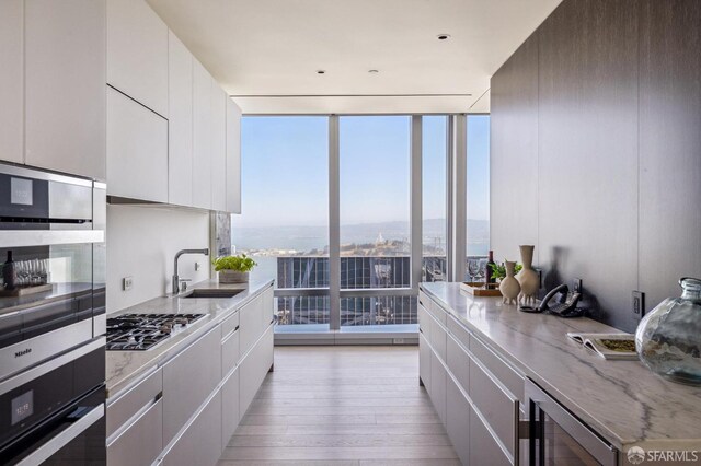 kitchen featuring white cabinets, appliances with stainless steel finishes, light wood-type flooring, and sink