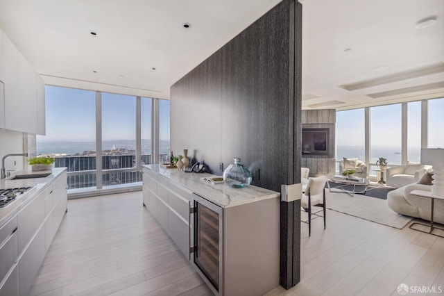 kitchen featuring white cabinets, a water view, a fireplace, and expansive windows