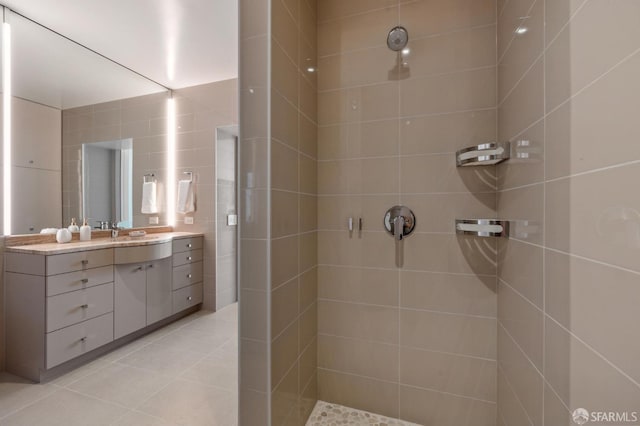 bathroom featuring a tile shower, vanity, tile walls, and tile patterned floors