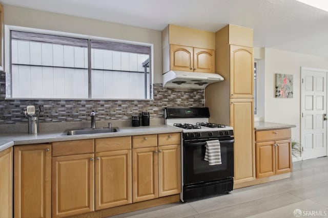 kitchen with gas stove, backsplash, light wood-type flooring, light brown cabinetry, and sink