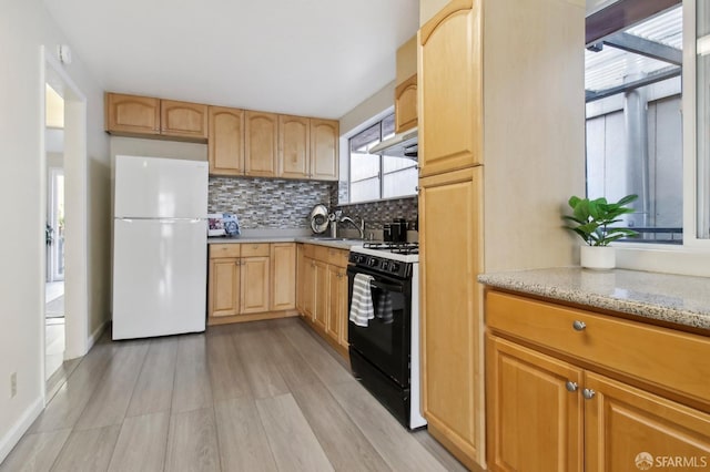 kitchen with sink, light hardwood / wood-style flooring, black range with gas cooktop, light stone countertops, and white refrigerator