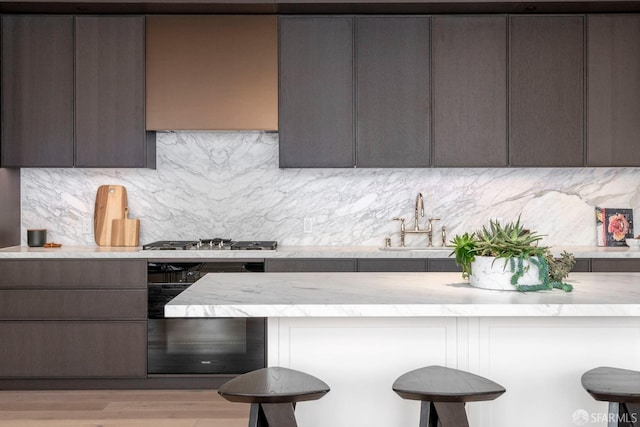 kitchen with modern cabinets, stainless steel gas cooktop, a breakfast bar, and a sink