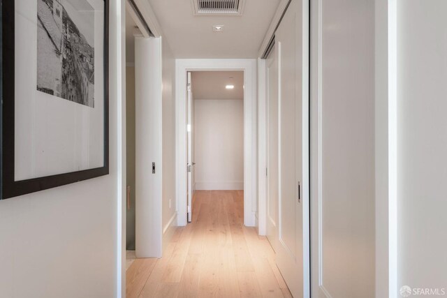 corridor featuring light wood-style flooring, visible vents, and baseboards