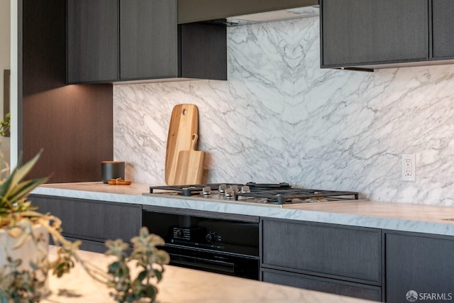 kitchen with gray cabinets, light countertops, stainless steel gas stovetop, decorative backsplash, and oven