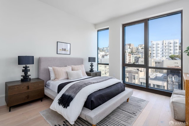 bedroom featuring light wood-style floors and a view of city