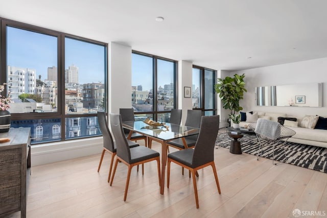 dining area with a wealth of natural light, a city view, and wood finished floors