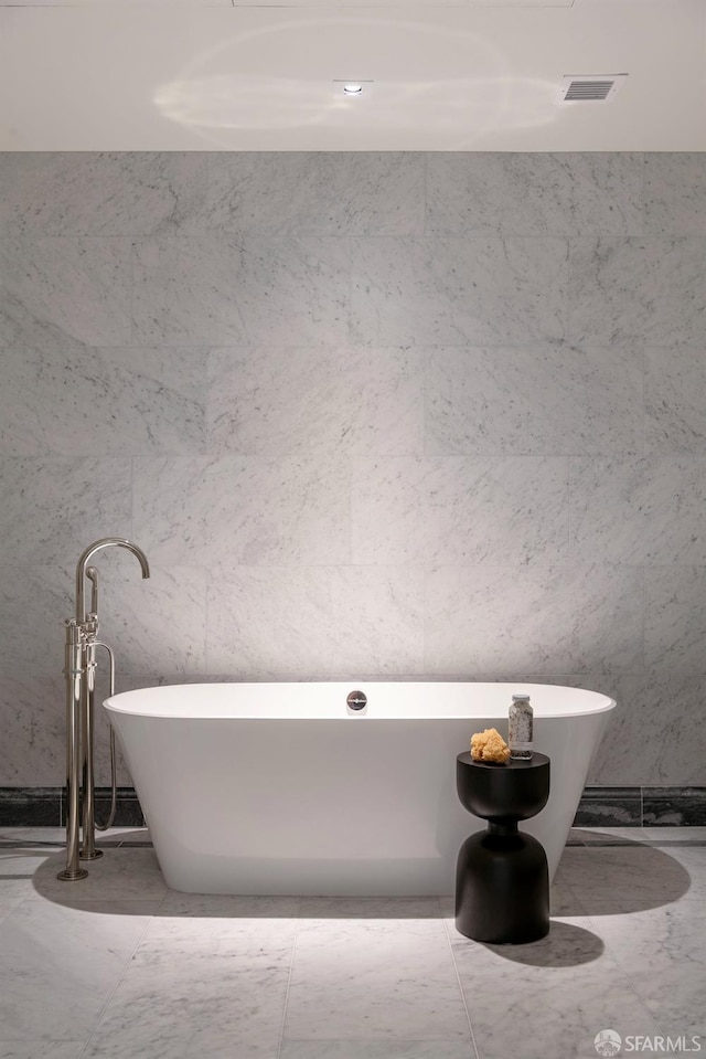 full bathroom featuring marble finish floor and a soaking tub