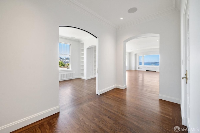 hallway with radiator heating unit, dark wood-type flooring, and ornamental molding