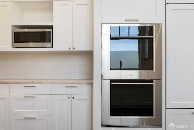 kitchen with white cabinets, appliances with stainless steel finishes, and decorative backsplash