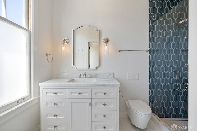 bathroom featuring a tile shower, vanity, and toilet