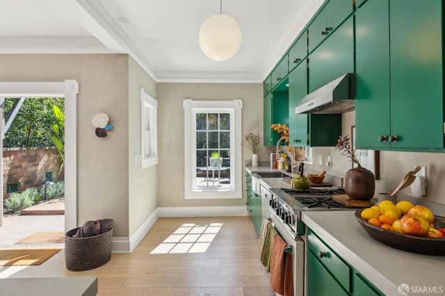 kitchen with green cabinetry, plenty of natural light, a sink, high end stove, and wall chimney exhaust hood