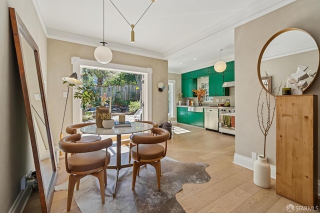 dining area with baseboards, crown molding, and light wood finished floors