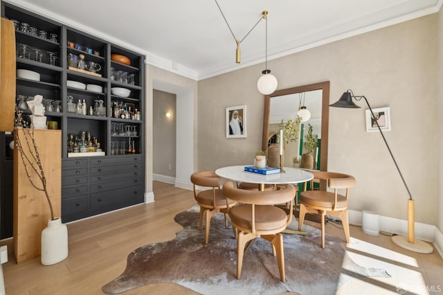 dining space featuring crown molding, baseboards, and wood finished floors