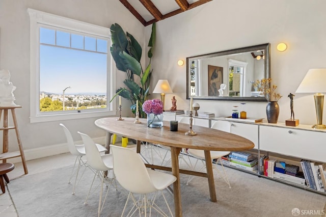 carpeted dining area featuring baseboards and vaulted ceiling with beams