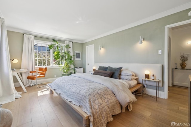 bedroom with hardwood / wood-style flooring, crown molding, and baseboards