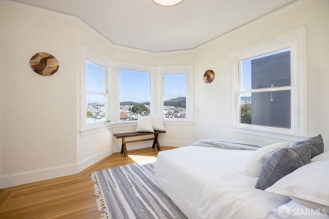 bedroom featuring crown molding, light wood-style floors, and baseboards