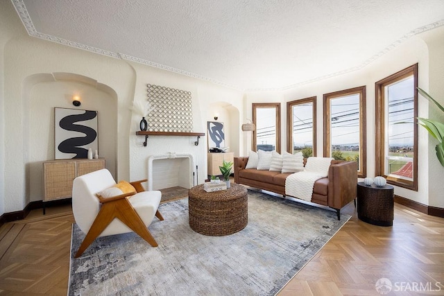 living area with baseboards, arched walkways, and a textured ceiling