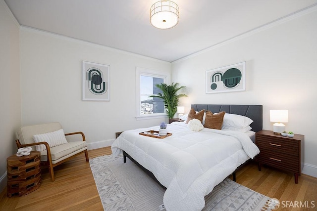 bedroom with crown molding, wood finished floors, and baseboards