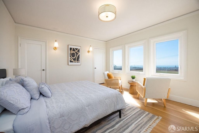 bedroom with crown molding, light wood-style flooring, and baseboards