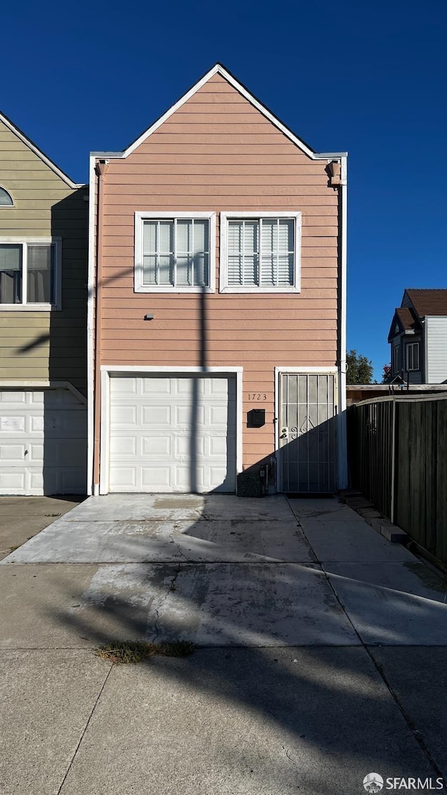 view of front facade featuring a garage, driveway, and fence