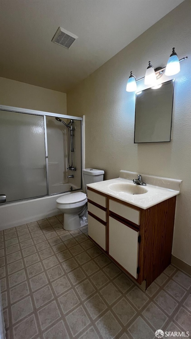 bathroom featuring visible vents, toilet, vanity, and combined bath / shower with glass door