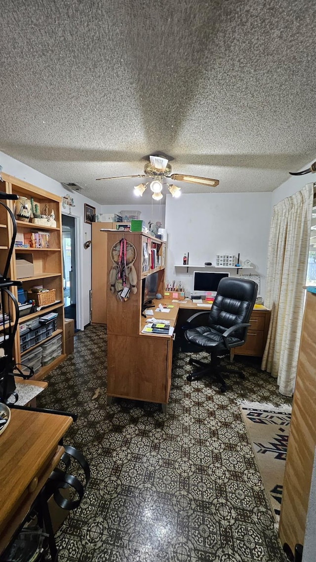 carpeted office space with a wealth of natural light, a textured ceiling, and ceiling fan