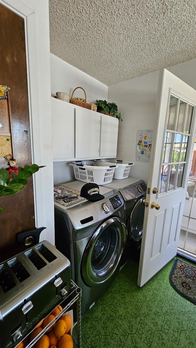 washroom featuring washer and clothes dryer, a textured ceiling, and cabinet space