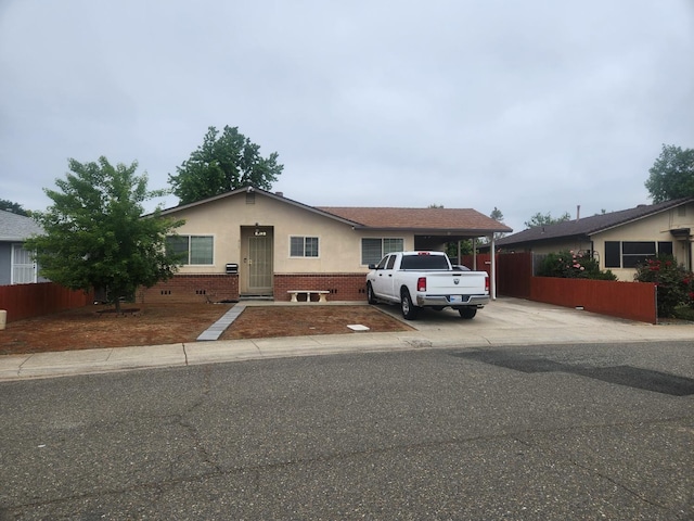 view of front of property featuring fence, stucco siding, brick siding, and concrete driveway