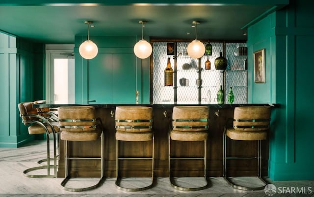 bar with green cabinets and hanging light fixtures