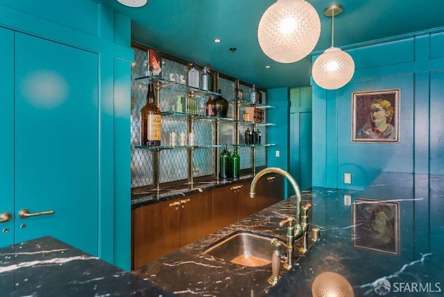 kitchen featuring pendant lighting, sink, and dark stone countertops