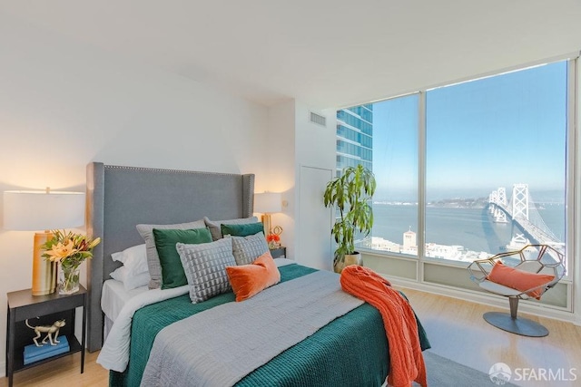 bedroom with a water view and light wood-type flooring