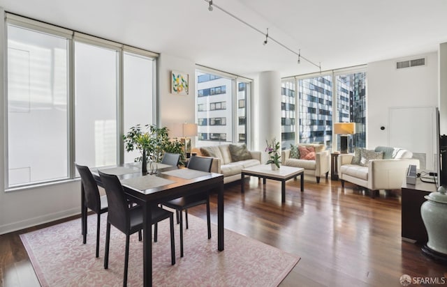 dining area featuring a wall of windows, track lighting, and dark hardwood / wood-style flooring