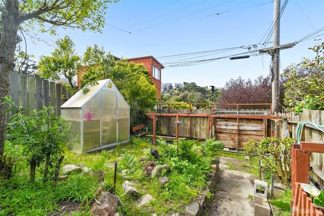 view of yard featuring a fenced backyard, an outdoor structure, and a greenhouse