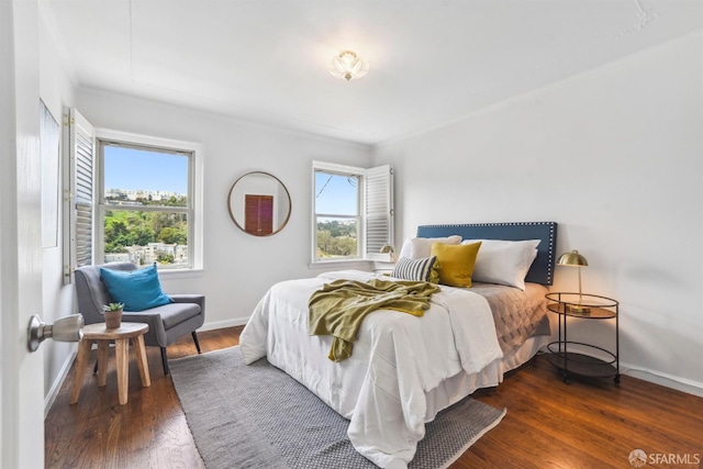 bedroom featuring baseboards, multiple windows, and wood finished floors