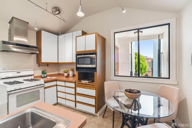 kitchen with white gas range, exhaust hood, stainless steel microwave, and vaulted ceiling