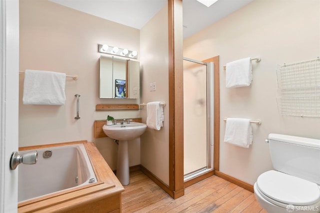 bathroom with toilet, a whirlpool tub, baseboards, wood finished floors, and a stall shower