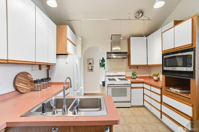 kitchen featuring wall chimney range hood, a sink, white appliances, light countertops, and white cabinetry