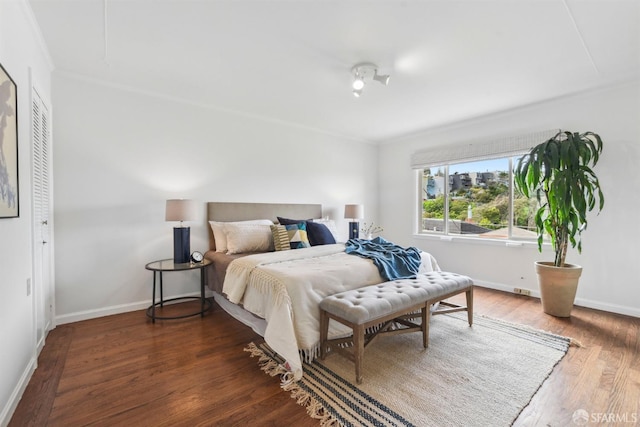 bedroom featuring baseboards, crown molding, and wood finished floors