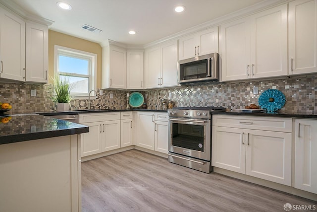 kitchen featuring white cabinets, decorative backsplash, stainless steel appliances, and sink