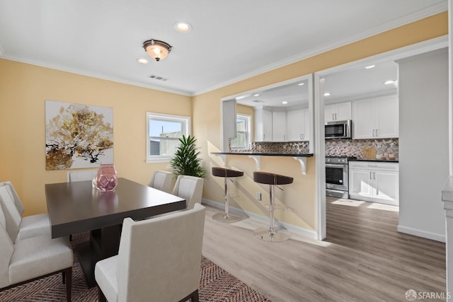 dining area with crown molding and hardwood / wood-style floors