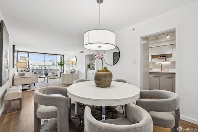 dining area with a wall of windows, wood finished floors, baseboards, and visible vents