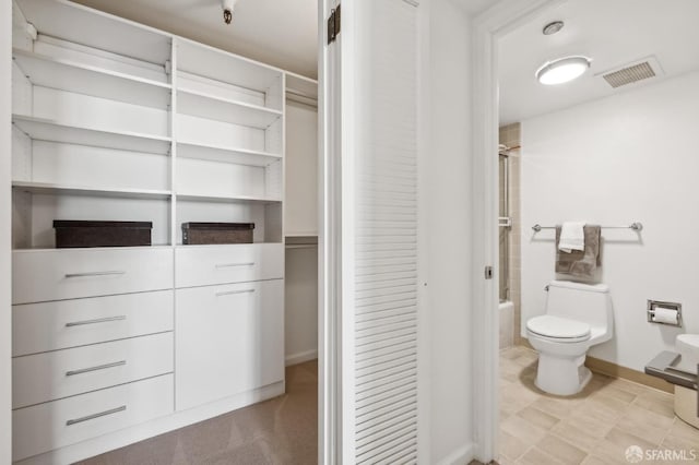 bathroom featuring baseboards, visible vents, toilet, and bathtub / shower combination