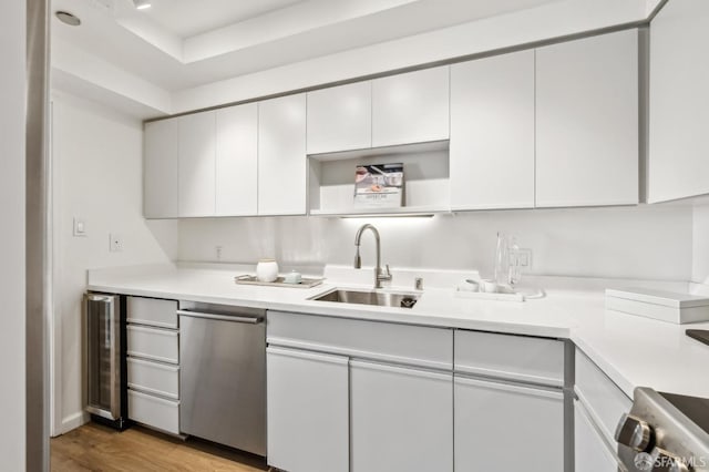 kitchen featuring light wood-type flooring, white cabinetry, light countertops, and a sink