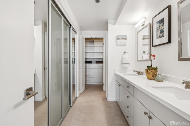 full bathroom featuring double vanity, a stall shower, a walk in closet, and a sink