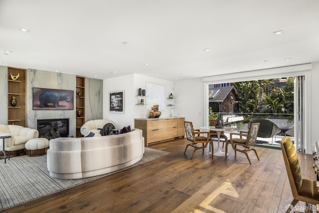 living room featuring hardwood / wood-style flooring, a premium fireplace, and built in shelves