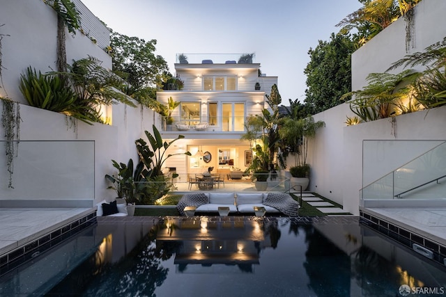 back house at dusk with a balcony