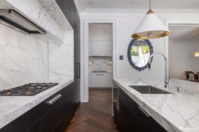 kitchen with sink, hanging light fixtures, backsplash, light stone counters, and dark parquet floors