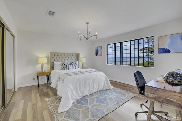 bedroom featuring light wood-type flooring, an inviting chandelier, and a closet