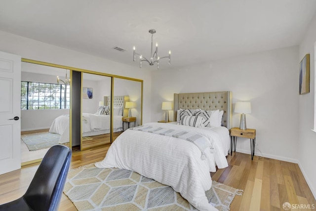 bedroom featuring a notable chandelier, light wood-type flooring, and a closet